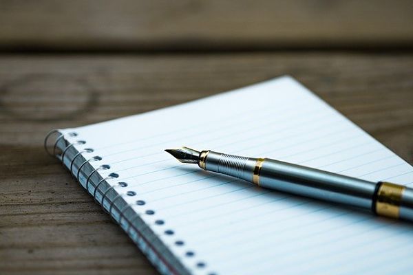 Un carnet avec un stylo plume argenté