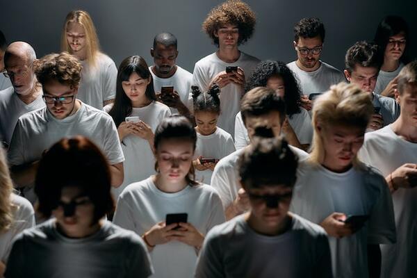 des personnes de sexe et d'âge différents sont en train de regarder leur écran de smartphone comme si elles étaient hypnotisées.