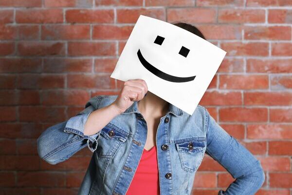 une jeune fille avec une feuille affichant un grand sourire devant le visage