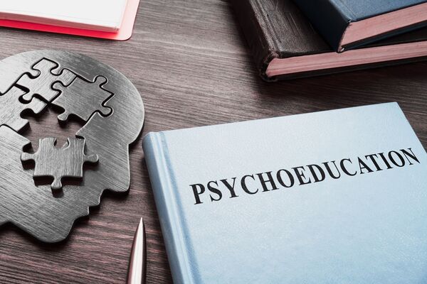 Sur un bureau, un livre est posé avec le titre "Psychoeducation".